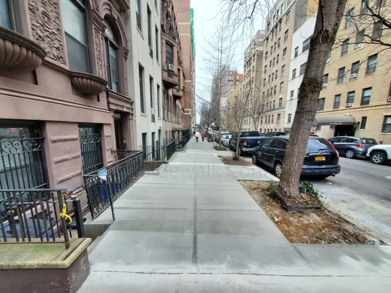 Completed concrete sidewalk running past Brooklyn brownstone homes