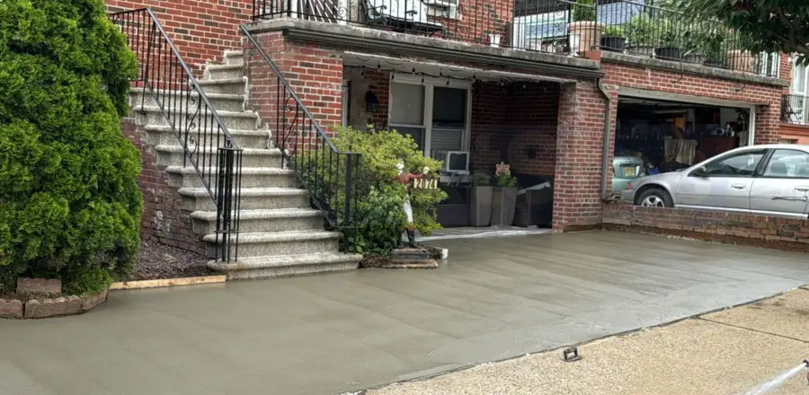 New concrete driveway and apron in front of a brick Brooklyn home